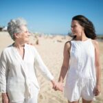 Joyful moment of a mother and daughter holding hands on a sunny beach in Portugal.